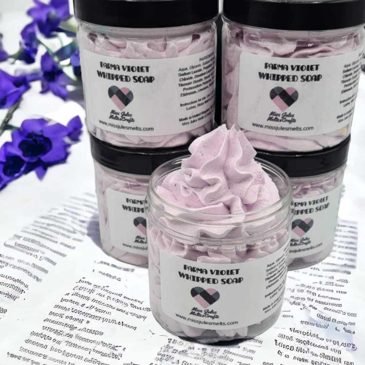 Four jars of Farms Vleckt Whipped Soap displayed on a printed sheet, with one open jar in front showing light purple whipped soap and three closed jars behind it.