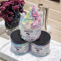 Three jars of Luvy Brubro Whipped Soap stacked on a marble tray in a bathroom setting, with a colorful whipped soap product on top and two black-lidded jars below.